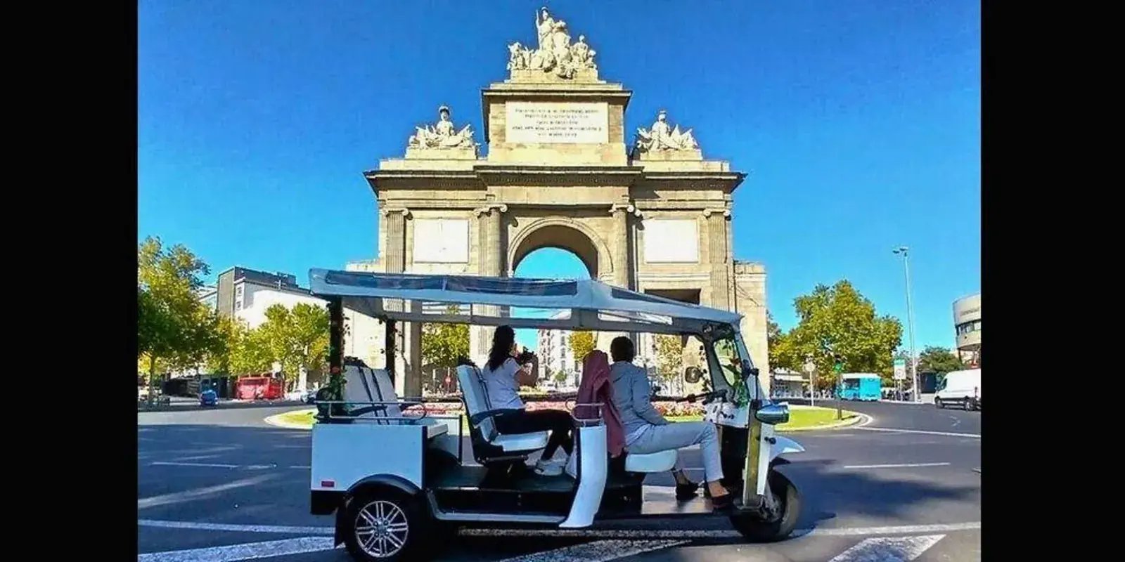 Tuk tuk with Puerta de Alcalá behind it