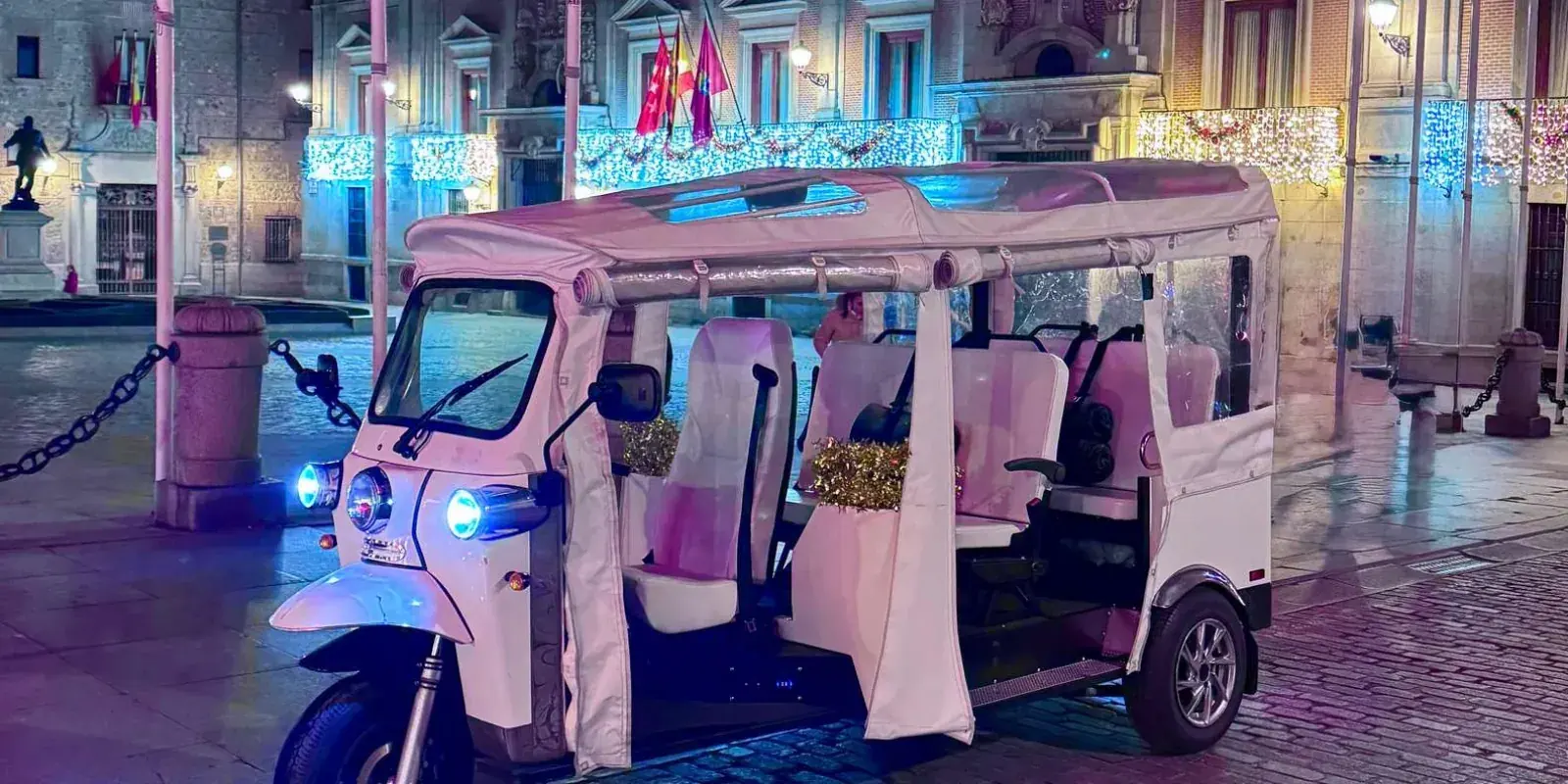 Electric tuk tuk beside illuminated buildings at night